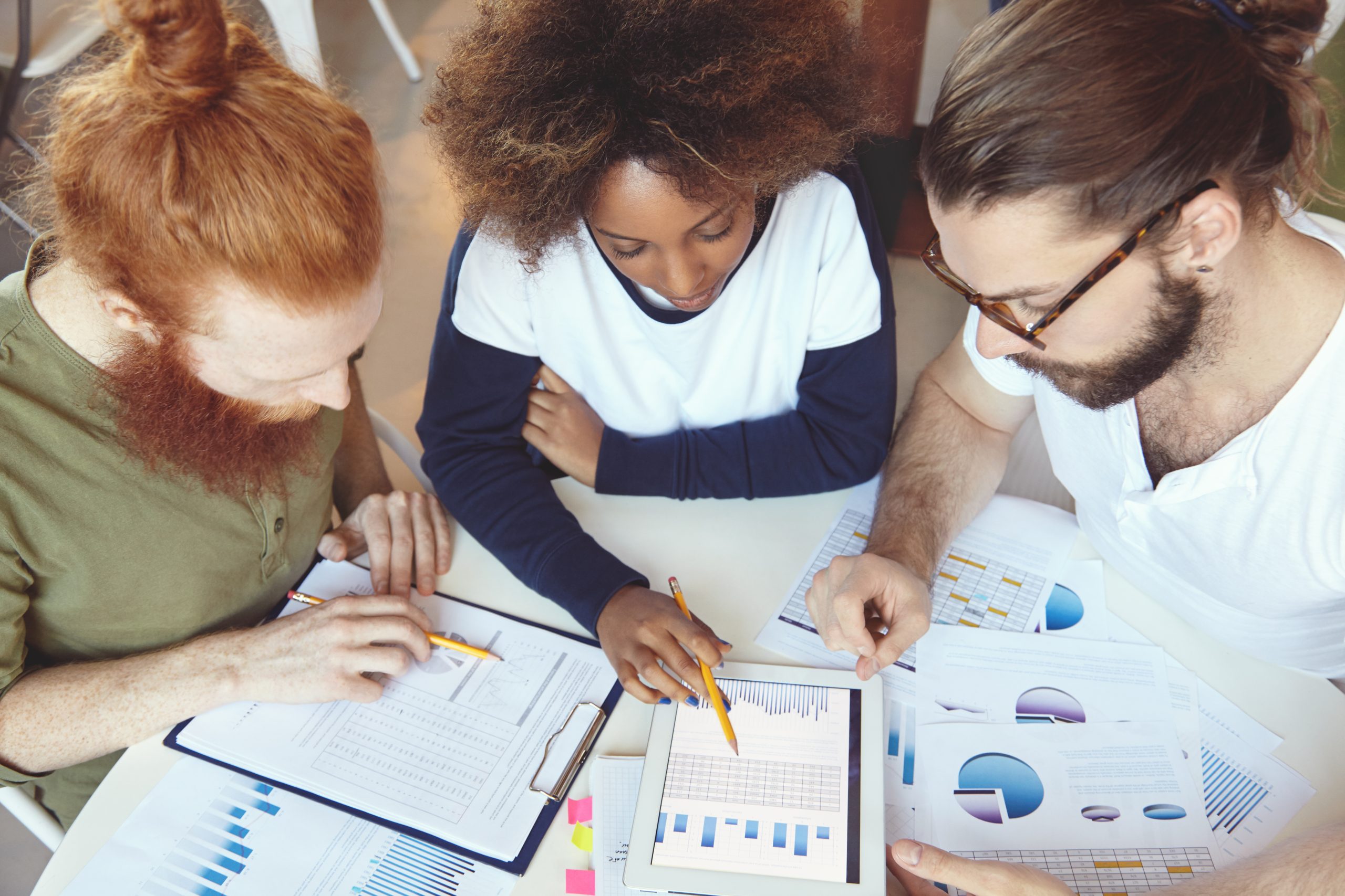 People working in team. Top view of partners discussing company's growth, making business research, analysing economic statistics and financial data in form charts and diagrams, using digital tablet